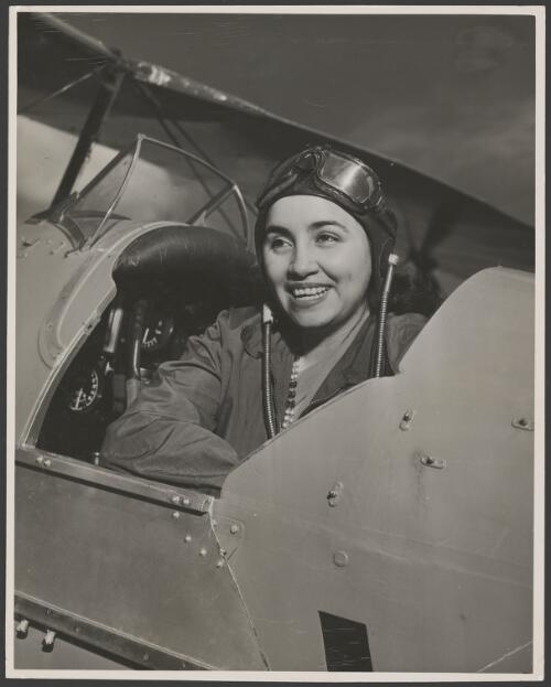 Portrait of Begum Haroom wearing flying cap in the cockpit of a biplane, ca. 1953 [picture]