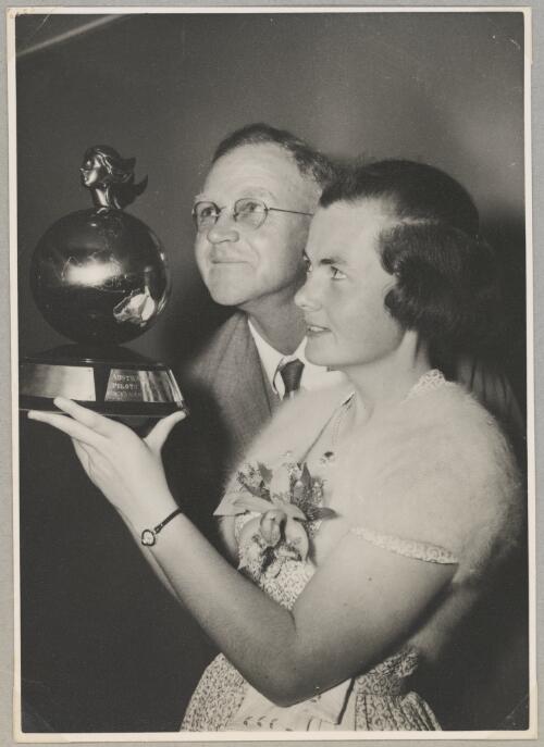 Portrait of Grace Cavanagh holding Australian Women Pilots' Association Air Reliability Trial trophy with her father Albert, Melbourne, 8 October 1955 [picture]
