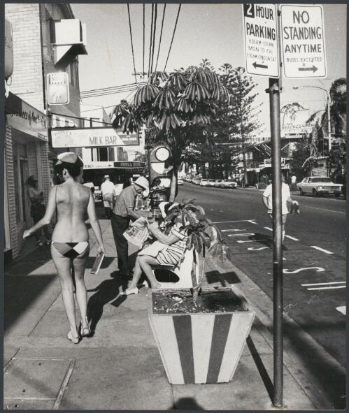 Girl in a swimsuit walking along the street outside the Surfer's Paradise Hotel, Surfer's Paradise, Queensland, ca. 1972 [picture] / Bruce Howard