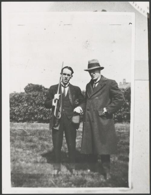 Man carrying a walking stick standing with a man in an overcoat, ca. 1925 [picture]