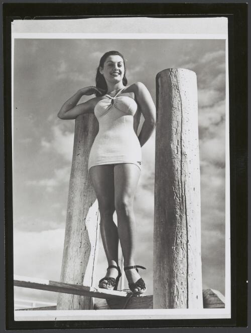 Model wears a Jantzen halterneck swimsuit at a jetty, ca. 1950 [picture]