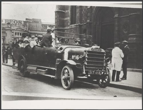 Group of office workers getting into a hard-wheeled Daimler charabanc outside St Paul's Cathedral on the way to a picnic, Melbourne, 1922 [picture]