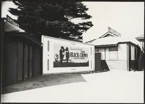 Advertising billboard for Griffith's Black Crows throat drops on a railway platform, next to the Goods and Livestock Railway Transport Office, Melbourne, ca. 1930 [picture]