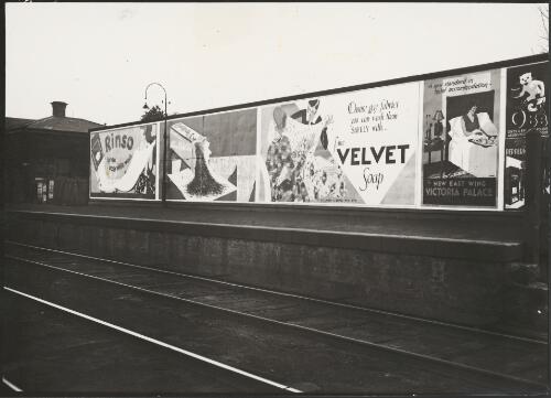 Advertising billboard for Rinso washing powder, Bushells Blue Label tea, Velvet soap, and accommodation at the Victoria Palace Hotel on a railway platform, Melbourne, ca. 1930 [picture]