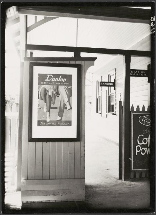 Advertising billboard for Dunlop men's and women's sports shoes on railway platform, Melbourne, ca. 1930 [picture]