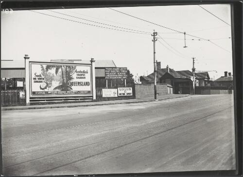 Advertising billboard for Queensland by the Queensland Government Tourist Bureau at a railway station, Toorak, Victoria, ca. 1930 [picture]