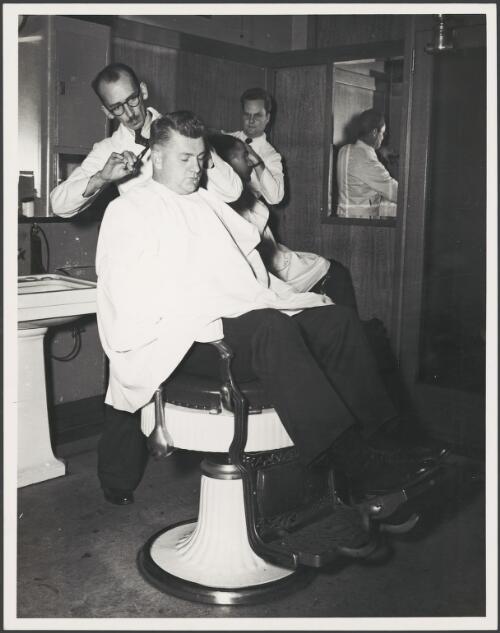 Two barbers cutting hair, Melbourne? 1949 [picture]