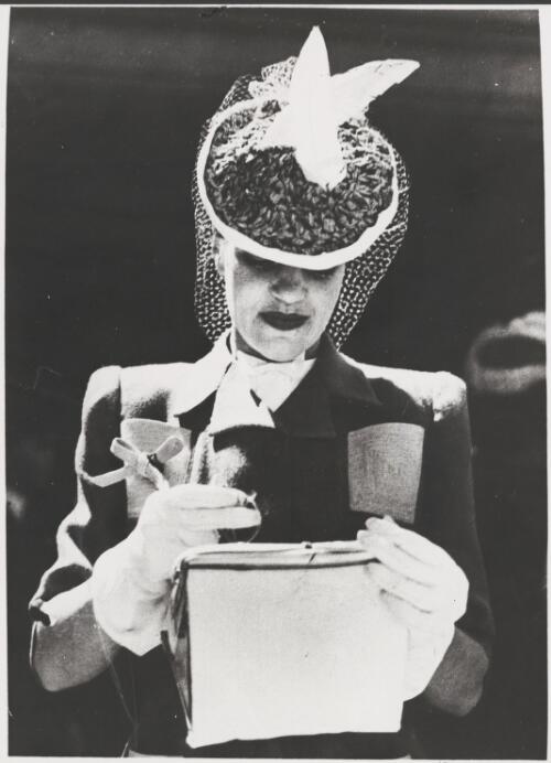 Woman at the Melbourne Cup wearing gloves and a hat with net and feather trim, Melbourne, 1944 [picture]