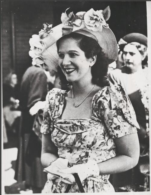 Mrs John Bovill wearing a floral print dress and a hat trimmed with large artificial flowers at Randwick races, Sydney, 13 July 1948 [picture]