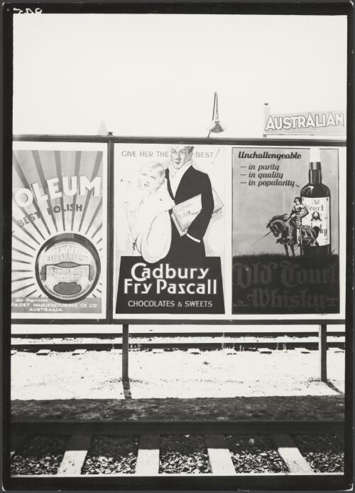 Advertising on billboards for Shinoleum floor polish, Cadbury Fry Pascall confectionery and Old Court whisky between two railway tracks, Melbourne, ca. 1930 [picture]