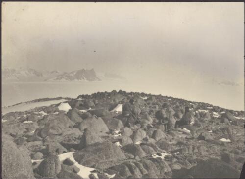 [Three party members sitting on rocks with snow capped peaks in the distance, Australasian Antarctic Expedition, 1911-1914] [picture]