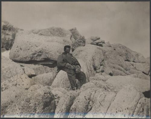 [A member of the party sitting on rocks, Australasian Antarctic Expedition, 1911-1914] [picture]/ Laseron