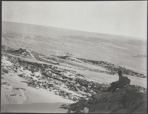 [The northern limit of the ice-cap at Cape Denison. Laseron sitting on Gneiss in situ, Australasian Antarctic Expedition, 1911-1914] [picture]/ Mawson