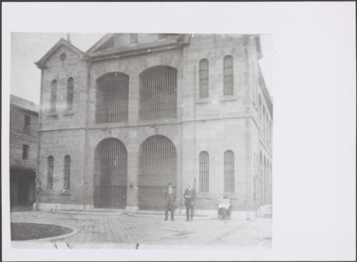 Three men in the yard in front of a two-storey building in Darlinghurst Gaol, Sydney, approximately 1918
