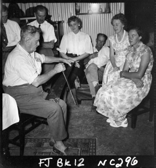 Entertaining visitors at Springvale, Tom Quilty plays his musical saw and enthralled them with his Irish melodies, Mrs Olive Quilty centre, Springvale Station, via Halls Creek, Kimberleys, Western Australia, 1956 [picture] / Frank H. Johnston