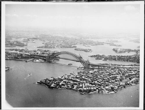 Aerial view of an incomplete Sydney Harbour Bridge looking west from Kirribilli, Sydney Harbour, 1931 [picture] / E.W. Searle