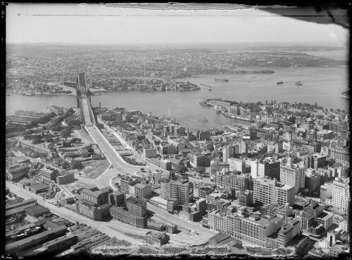 Aerial view of the Bradfield Highway, the Sydney Harbour Bridge and Circular Quay, Sydney Harbour, ca. 1935 [picture] / E.W. Searle