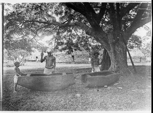 Two men playing wooden drums, watched by two young boys, Fiji, ca. 1920 [picture] / E.W. Searle
