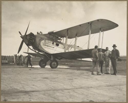 Group of men including Captain Holden standing by the wing tip of G-AUHW, a De Havilland 61 Giant Moth named Canberra, Australia, ca. 1932 [picture] / E.W. Searle