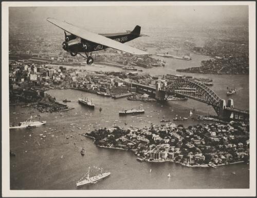 Southern Cross, VH-USU, a Fokker F.VIIa/3m, flying over the Sydney Harbour Bridge, ca. 1933 [picture] / E.W. Searle