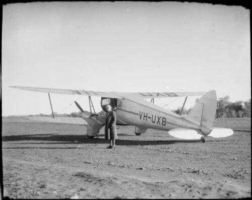 Mrs Searle standing beside a bi-plane marked VH-UXB, Hermannsburg Mission, Finke River, Northern Territory, 1947 [picture] / E.W. Searle