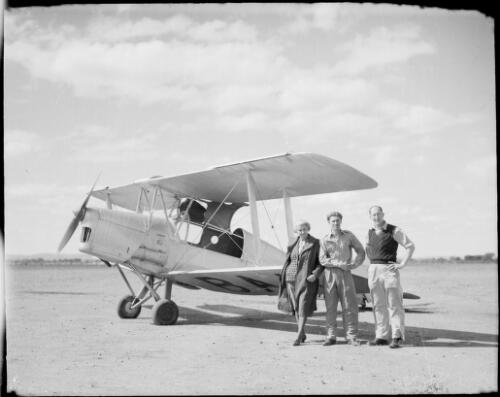 Mrs Searle and two men standing beside a bi-plane VH-BA?, Hermannsburg Mission, Finke River, Northern Territory, 1947 [picture] / E.W. Searle