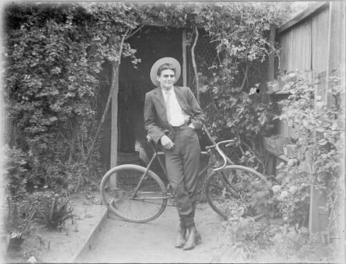 Man wearing a boater hat leaning against a bicycle, Australia, ca. 1900 [picture]
