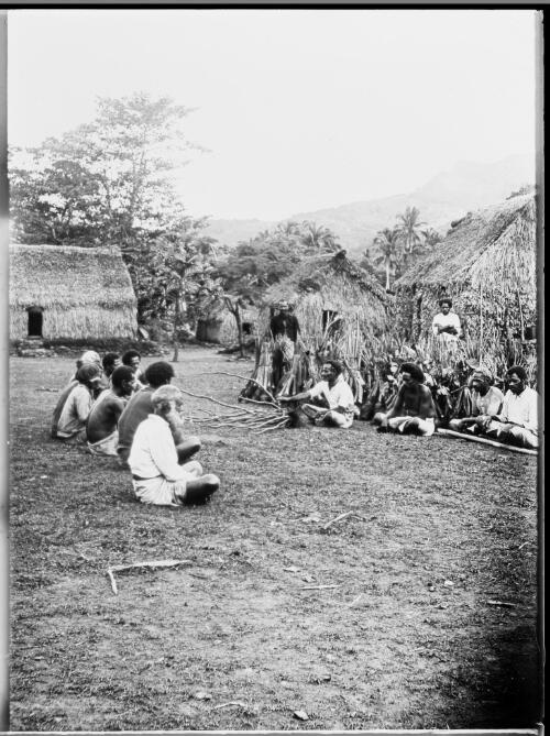 Two groups of seated men, facing each other in a village, Fiji, ca. 1920 [picture] / E.W. Searle