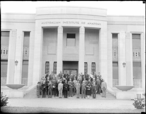 Group of men and women standing on the front steps of the Australian Institute of Anatomy, Canberra, ca. 1949, 1 [picture] / E.W. Searle