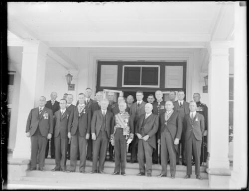 Group of men wearing medals, in an internal courtyard of old Parliament House [?], Canberra, ca. 1927, 2 [picture] / E.W. Searle