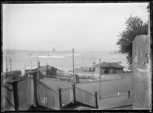 HMAS Sydney beyond the Man-o-War Steps viewed from Bennelong Point, Sydney Harbour, ca. 1920 [picture] / E.W. Searle