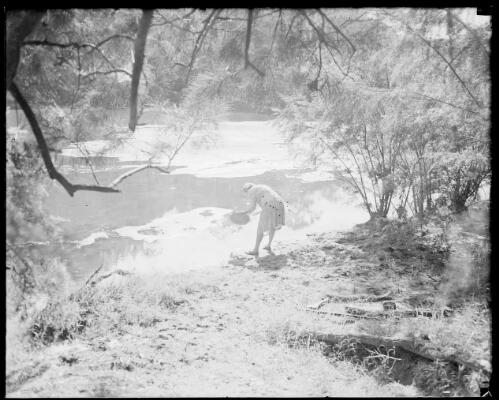 Mrs Searle washing a pan in a creek, Australia, ca. 1945 [picture] / E.W. Searle