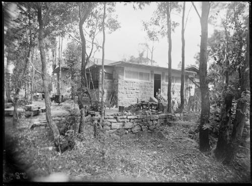 People sitting by a doorway of house made of stone blocks, Australia, ca. 1945 [picture] / E.W. Searle