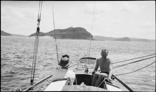 Two men in a sailing boat with Barrenjoey Head in the background, Barrenjoey Head, New South Wales, ca. 1945, 1 [picture] / E.W. Searle