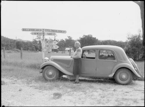 Mrs Searle beside E.W. Searle's Citroen with the Bulahdelah signpost, New South Wales, ca. 1949 [picture] / E.W. Searle