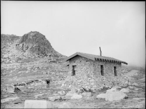 Mrs Searle beside Seaman's Hut on the slopes of Mount Kosciuscko [i.e. Kosciuszko], New South Wales, ca. 1949 [picture] / E.W. Searle