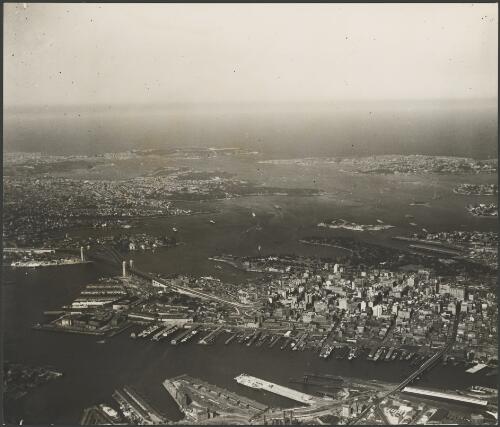 Aerial view of the Sydney Harbour Bridge, the city and the Harbour to the Heads, Sydney Harbour, ca. 1935 [picture] / E.W. Searle