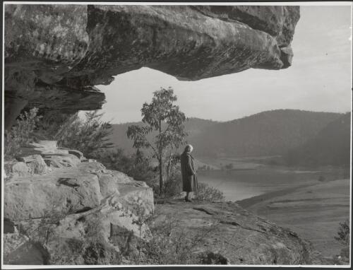 Mrs Searle standing at the mouth of Court House Cave, Wisemans Ferry, Hawkesbury River, New South Wales, ca. 1945, 1 [picture] / E.W. Searle