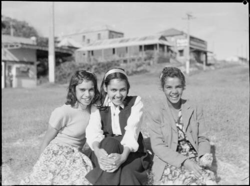Three seated young girls, with houses in the background, Australia, ca. 1945 [picture] / E.W. Searle