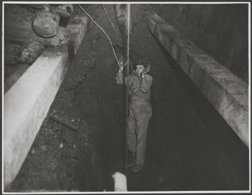 Man being lowered by rope down a mineshaft, Australia, ca. 1935 [picture] / E.W. Searle