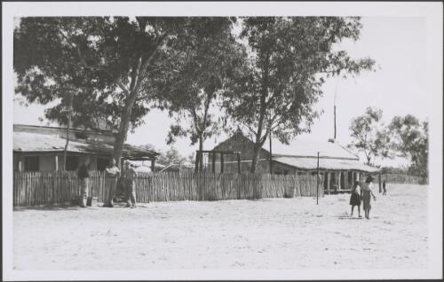 People beside a picket fence, with two houses behind, Northern Territory, 1947 [picture] / E.W. Searle