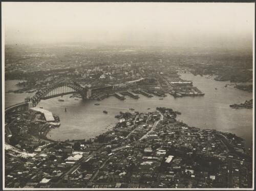 Aerial view of an incomplete Sydney Harbour Bridge with McMahon's Point in the foreground, Sydney Harbour, 1931, 2 [picture] / E.W. Searle