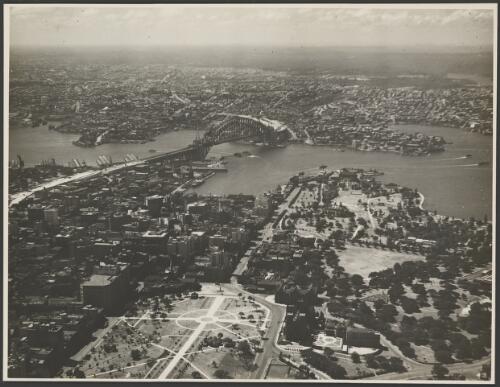 Aerial view of an incomplete Sydney Harbour Bridge with Hyde Park in the foreground, Sydney Harbour, 1931 [picture] / E.W. Searle