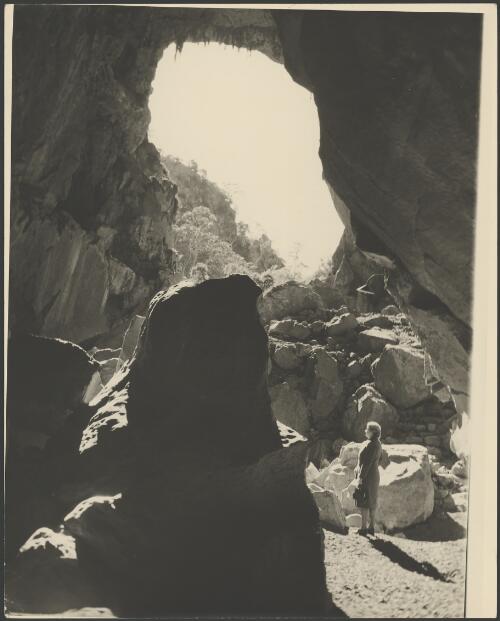 Mrs Searle standing in a rock filled opening, Northern Territory, 1947 [picture] / E.W. Searle