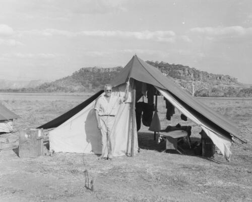 Setzler standing in front of our sleeping tent, Gallery Hill, "Einyaluk" and escarpment in background, Oenpelli, October 1948 [picture]