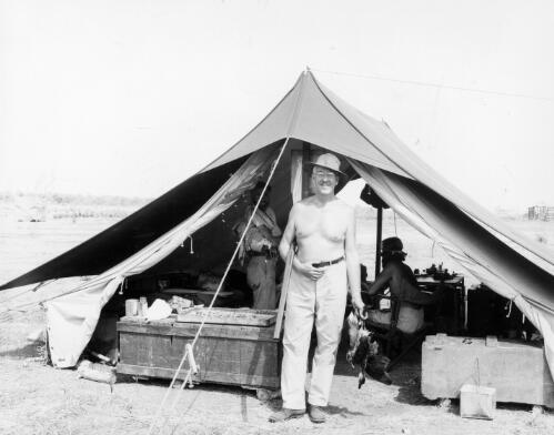 Frank Setzler standing in front of sleeping tent and holding two whistling ducks shot this morning, Oenpelli, 27 October 1948 [picture]