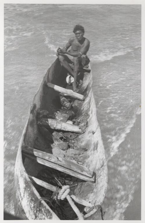 Korpitja sitting in stern of typical dug-out canoe being towed behind Fred Gray's motor launch on our way to take-off in Catalina, July 1948 [picture] / Frank M. Setzler