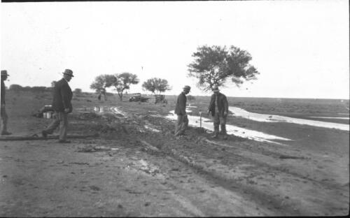 Bog near Boolambo [Four men standing on a boggy road] [transparency] : a deputation lantern slide of the AIM [Australian Inland Mission] Head Office, 1926-1940 / [John Flynn?]