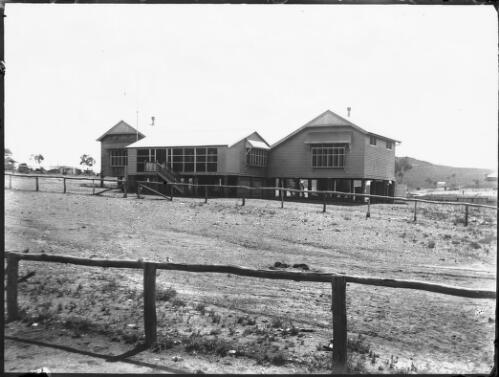 Unidentified building behind a road [picture] : Fred McKay Cape York Peninsula and West Queensland Patrol 1938-1940 / [Fred McKay]