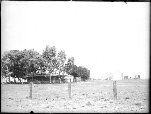 Unidentified buildings with fence in foreground [picture] : Fred McKay Cape York Peninsula and West Queensland Patrol 1938-1940 / [Fred McKay]